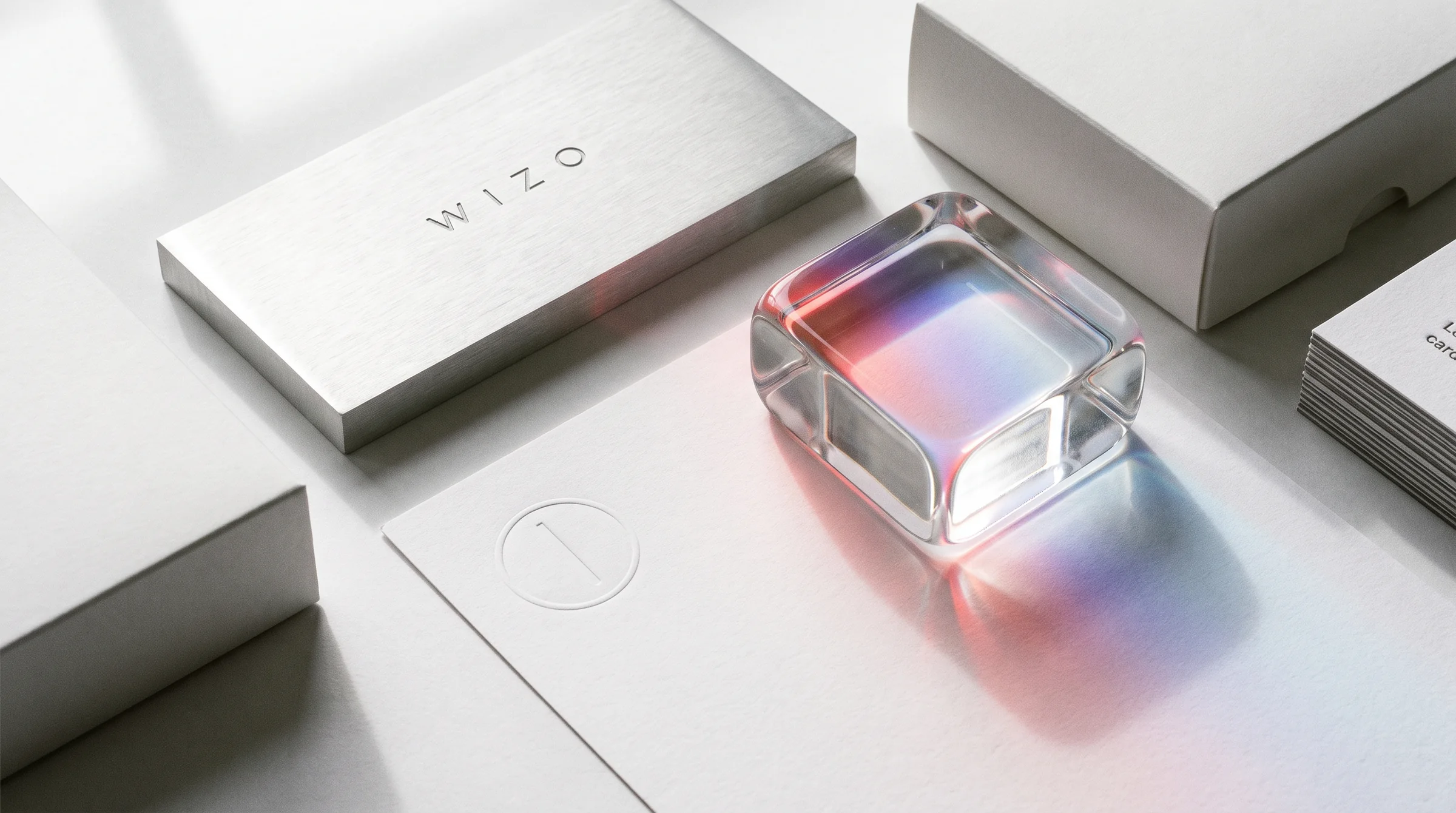 An engraved aluminium plaque, embossed paper and a glass block splitting light into colours.